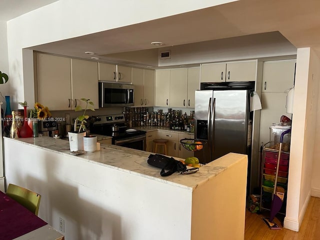 kitchen featuring light hardwood / wood-style floors, stainless steel appliances, and kitchen peninsula