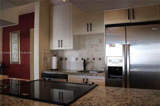 kitchen with tasteful backsplash, stainless steel refrigerator with ice dispenser, white cabinetry, and sink