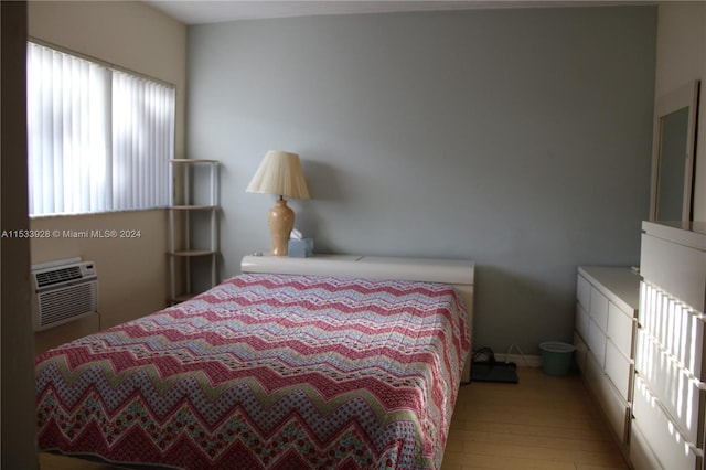 bedroom with a wall unit AC and light wood-type flooring