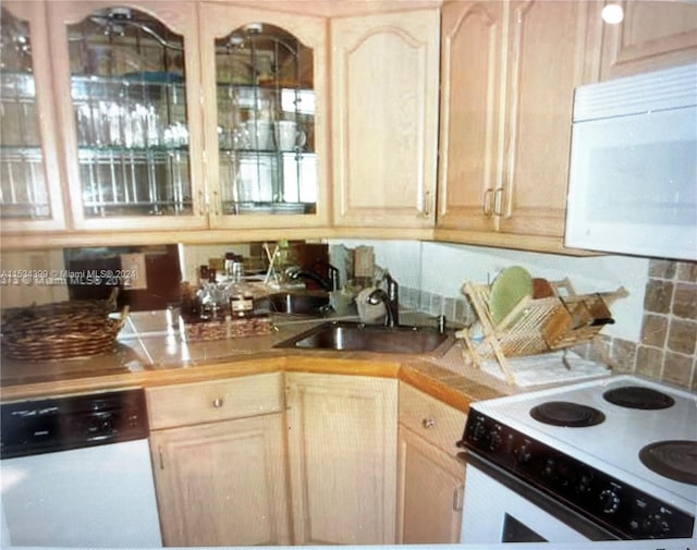 kitchen with decorative backsplash, light brown cabinets, white appliances, and sink