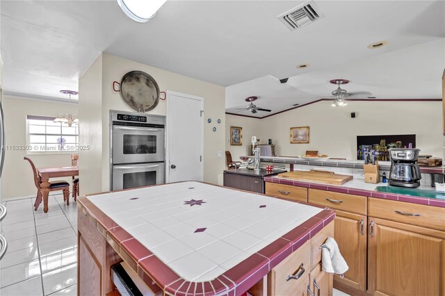 kitchen featuring light tile patterned floors, vaulted ceiling, a center island, tile countertops, and stainless steel double oven