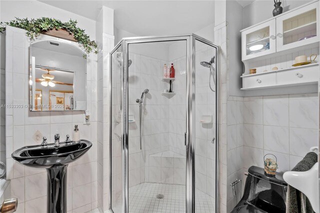 bathroom with toilet, an enclosed shower, and tile walls