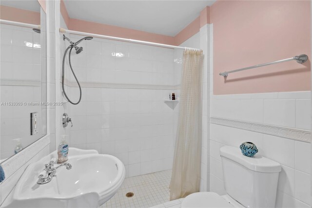 bathroom featuring a shower with shower curtain, toilet, sink, and tile walls