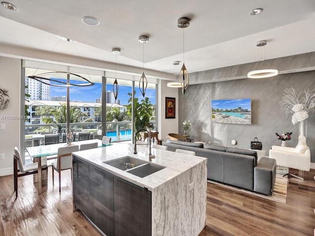 kitchen featuring a center island with sink, decorative light fixtures, sink, and a wealth of natural light