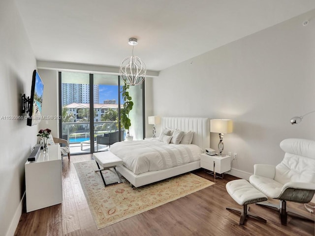 bedroom featuring an inviting chandelier, hardwood / wood-style floors, and access to exterior