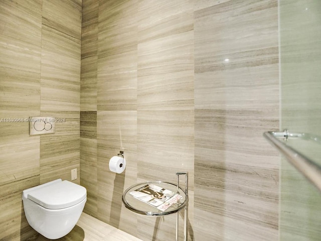 bathroom featuring tile walls and toilet