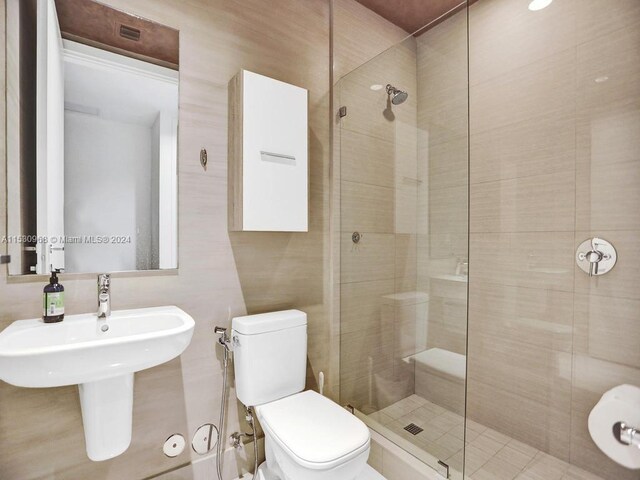 bathroom featuring a shower with door and toilet