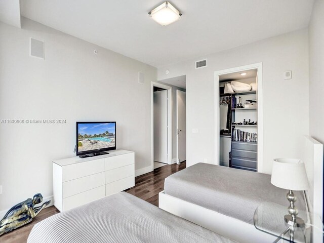 bedroom featuring a closet, dark hardwood / wood-style floors, and a walk in closet