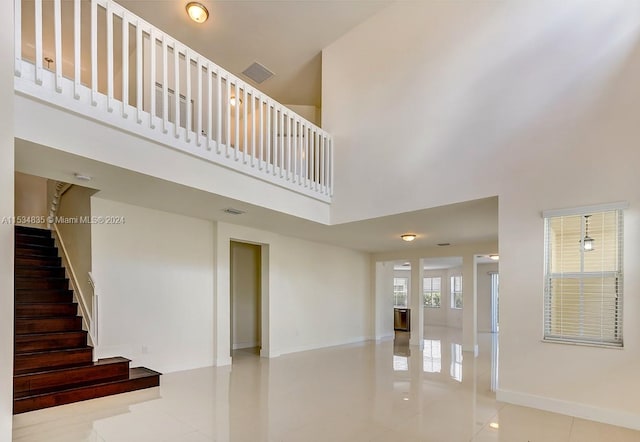 stairway with light tile floors and a high ceiling