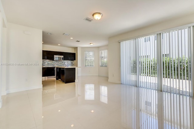 interior space with backsplash, dark brown cabinetry, and light tile flooring