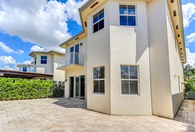 back of property with a balcony and a patio