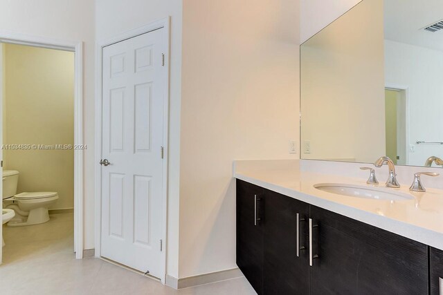 bathroom featuring oversized vanity, toilet, and tile floors