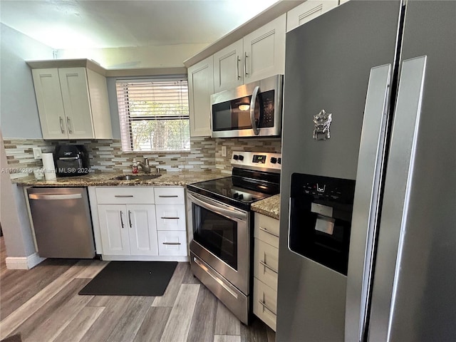 kitchen featuring stainless steel appliances, stone countertops, light hardwood / wood-style flooring, white cabinetry, and sink