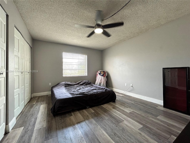 bedroom featuring dark hardwood / wood-style flooring, a textured ceiling, and ceiling fan