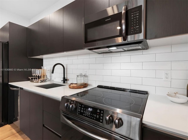 kitchen with light hardwood / wood-style floors, tasteful backsplash, sink, and stainless steel appliances