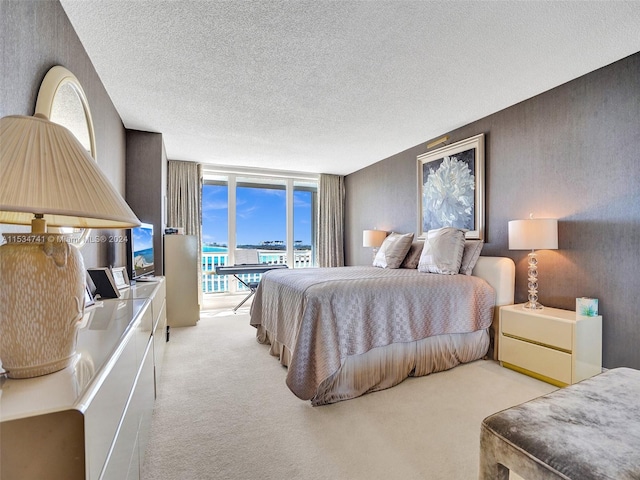 carpeted bedroom with a wall of windows, access to outside, and a textured ceiling