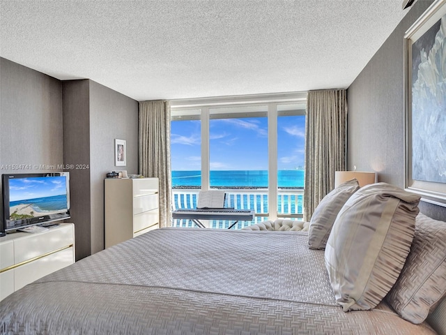 bedroom featuring a water view and a textured ceiling