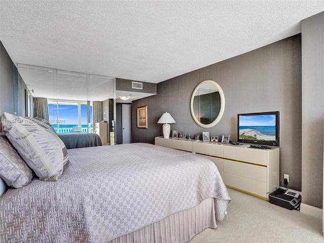 bedroom featuring light carpet and a textured ceiling