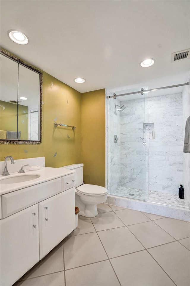 bathroom with toilet, vanity with extensive cabinet space, tile flooring, and tiled shower