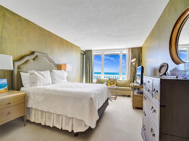 carpeted bedroom featuring a water view, a textured ceiling, and wooden walls