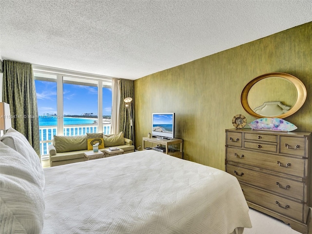 carpeted bedroom featuring a water view, a textured ceiling, and access to exterior