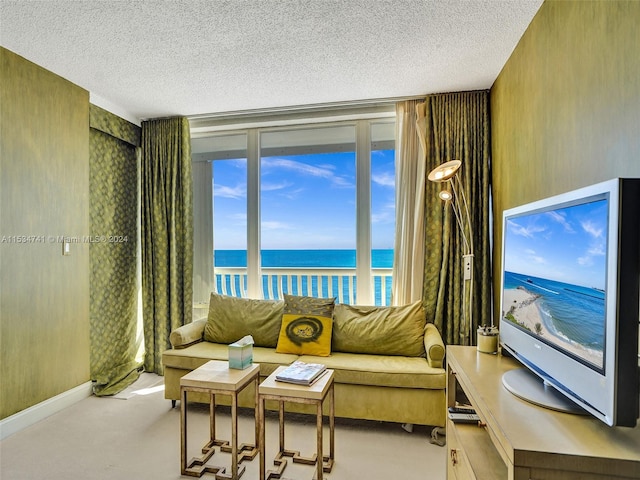 interior space with light carpet, a water view, and a textured ceiling