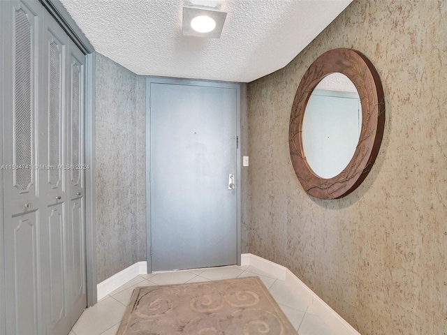 doorway featuring light tile floors and a textured ceiling