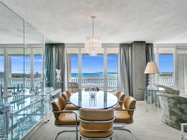 carpeted dining space with floor to ceiling windows, an inviting chandelier, a water view, and a textured ceiling