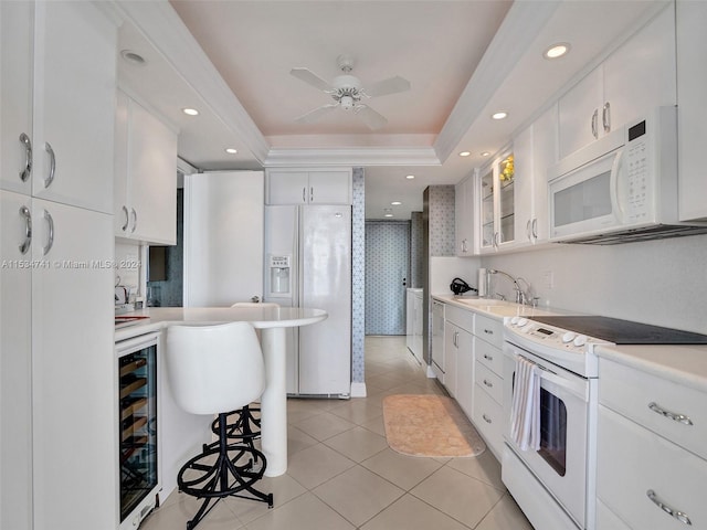 kitchen with ceiling fan, wine cooler, white appliances, white cabinets, and a tray ceiling