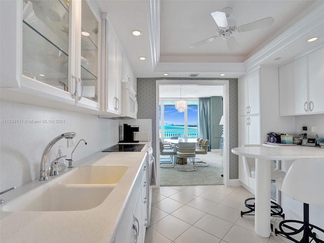 kitchen featuring ceiling fan with notable chandelier, white appliances, white cabinets, a raised ceiling, and sink