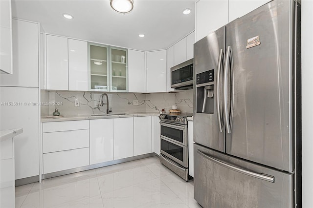 kitchen with tasteful backsplash, stainless steel appliances, white cabinetry, and sink