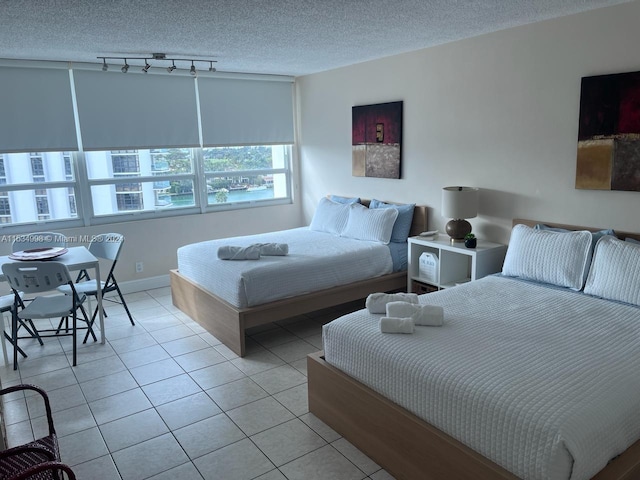 tiled bedroom featuring a textured ceiling and track lighting