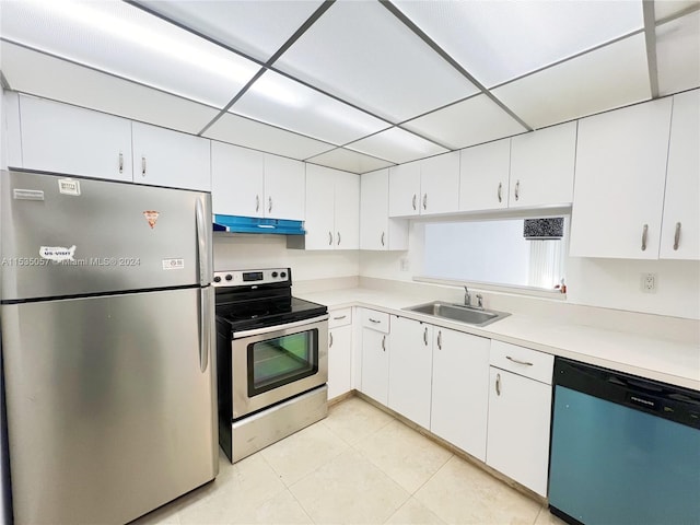 kitchen featuring appliances with stainless steel finishes, light tile patterned floors, sink, white cabinets, and a drop ceiling