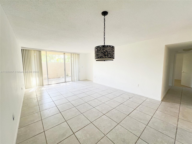 unfurnished room featuring a wall of windows, a textured ceiling, and light tile patterned floors