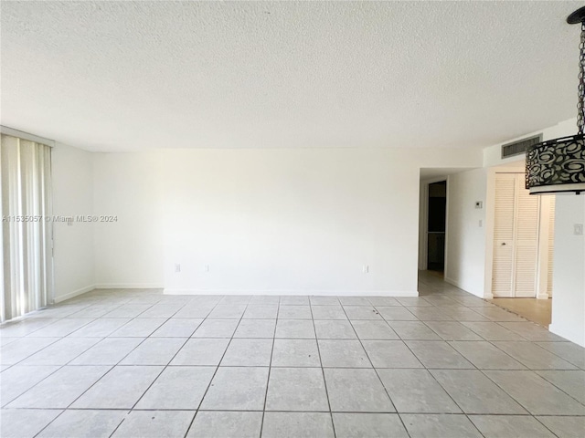 unfurnished room with a textured ceiling and light tile patterned floors