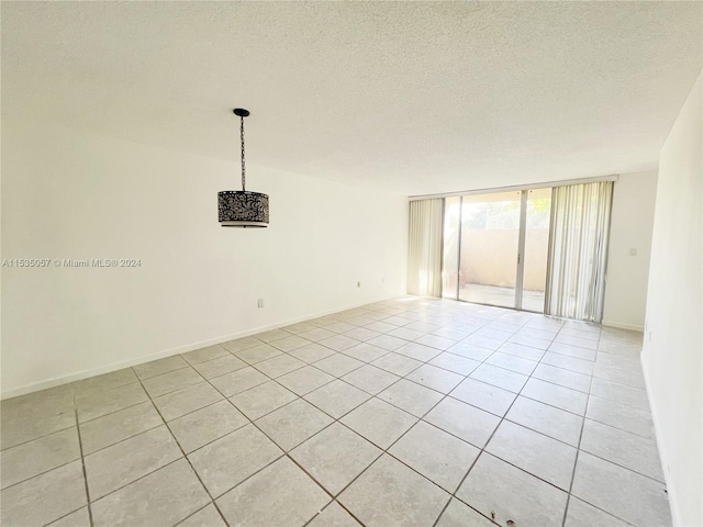 unfurnished room featuring expansive windows, a textured ceiling, and light tile patterned floors