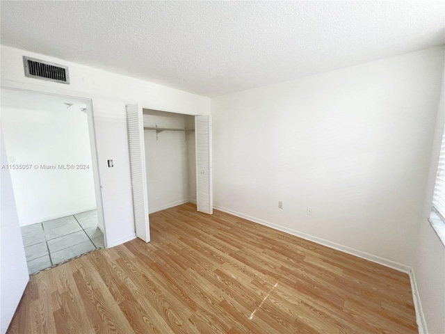 unfurnished bedroom with a textured ceiling and light wood-type flooring