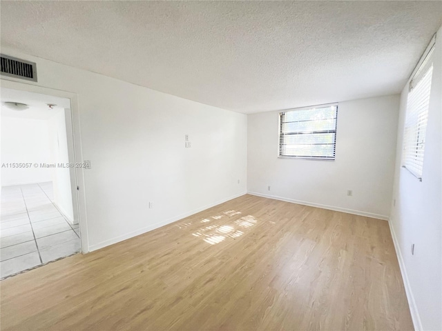 unfurnished room with light hardwood / wood-style floors and a textured ceiling