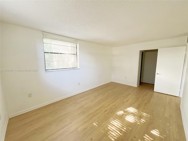 empty room with light hardwood / wood-style floors and a textured ceiling