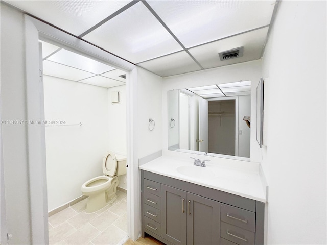 bathroom with vanity, toilet, and a drop ceiling