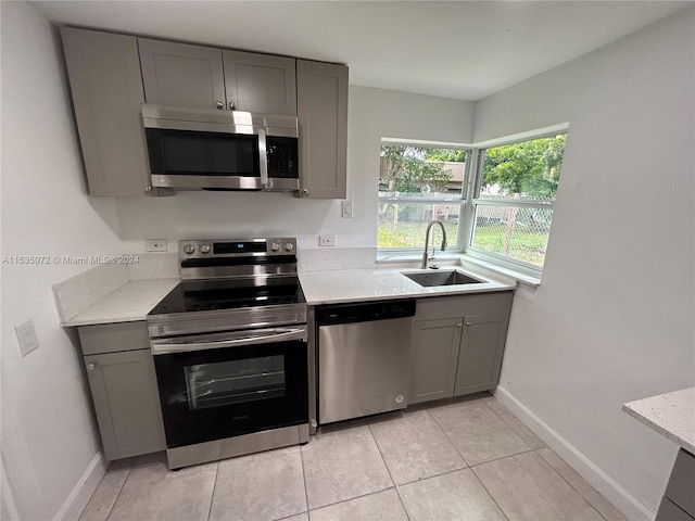 kitchen featuring gray cabinetry, light tile floors, appliances with stainless steel finishes, and sink