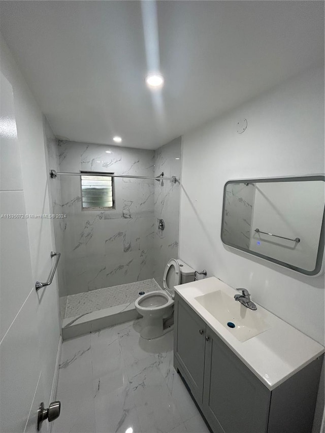 bathroom with toilet, a tile shower, tile floors, and vanity