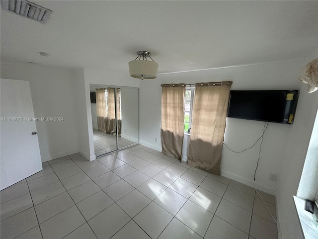 unfurnished bedroom featuring a closet and light tile floors