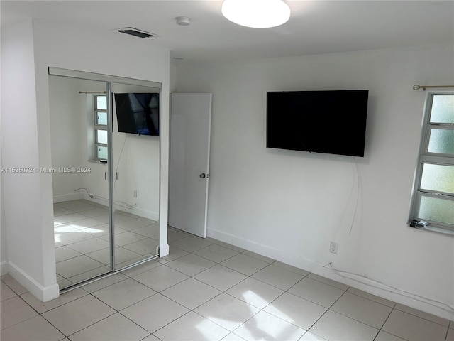 unfurnished bedroom featuring light tile flooring and a closet