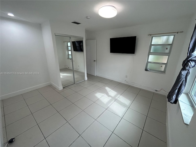 unfurnished bedroom featuring a closet and light tile flooring