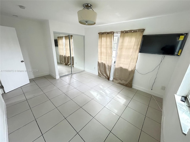 unfurnished bedroom featuring a closet and light tile floors