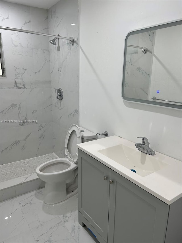 bathroom with toilet, tile floors, a tile shower, and vanity