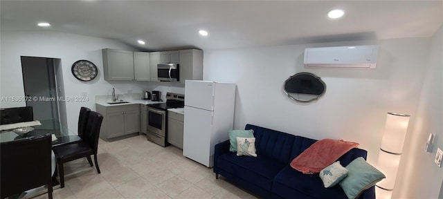 kitchen featuring gray cabinetry, appliances with stainless steel finishes, light tile floors, and an AC wall unit