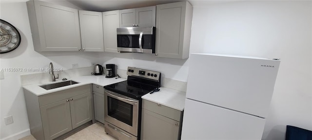 kitchen featuring light tile floors, gray cabinets, sink, and stainless steel appliances