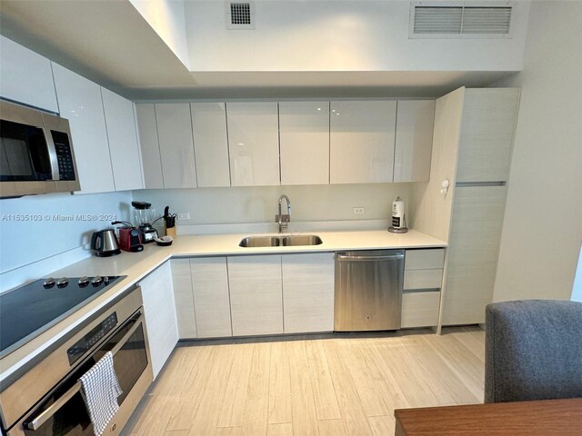 kitchen featuring white cabinets, light hardwood / wood-style flooring, appliances with stainless steel finishes, and sink